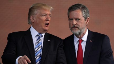 President Donald Trump and Jerry Falwell, Jr. huddle close together on stage at Liberty University in 2017.