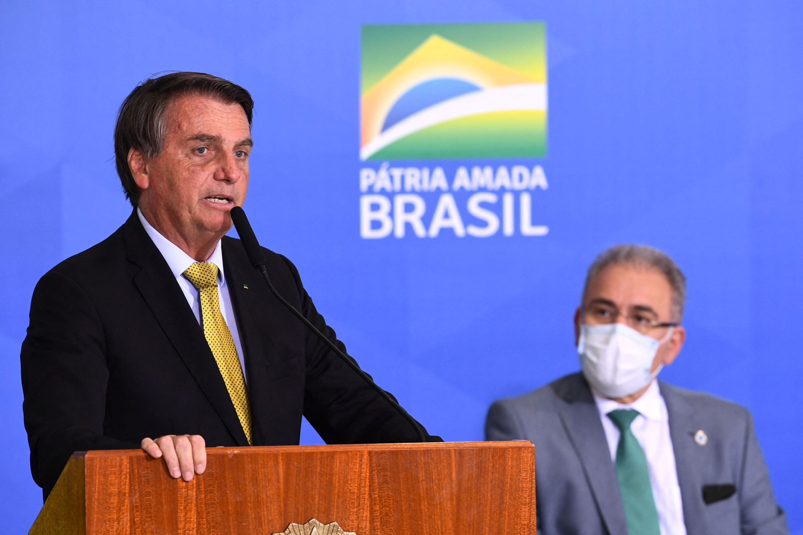 Brazilian President Jair Bolsonaro (L) speaks near Health Minister Marcelo Queiroga