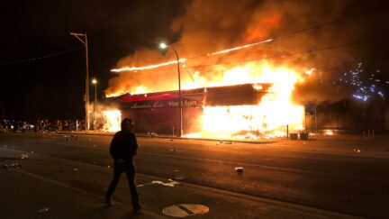 Flames rise from a liquor store near the Third Police Precinct on May 28, 2020 in Minneapolis, Minnesota, during a protest over the death of George Floyd, an unarmed black man, who died after a police officer kneeled on his neck for several minutes. - A police precinct in Minnesota went up in flames late on May 28 in a third day of demonstrations as the so-called Twin Cities of Minneapolis and St. Paul seethed over the shocking police killing of a handcuffed black man. The precinct, which police had abandoned, burned after a group of protesters pushed through barriers around the building, breaking windows and chanting slogans. A much larger crowd demonstrated as the building went up in flames.