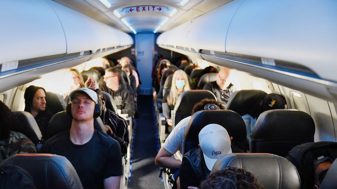 Airline passengers, some not wearing face masks following the end of Covid-19 public transportation rules, sit during a American Airlines flight operated by SkyWest Airlines from Los Angeles International Airport (LAX) in California to Denver, Colorado on April 19, 2022. - Mask mandates on public transportation are no longer in effect following a ruling by federal judge on April 18, 2022. (Photo by Patrick T. FALLON / AFP) (Photo by PATRICK T. FALLON/AFP via Getty Images)