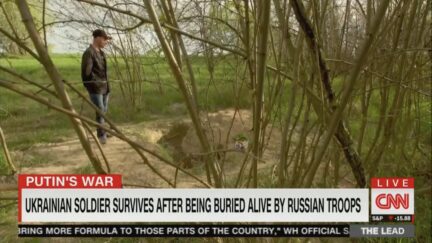 A Ukrainian soldier stands next to the grave where Russians buried him alive.