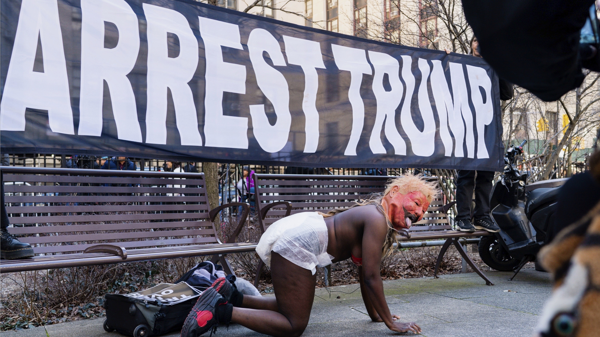 A woman performs wearing a mask of former president Donald Trump as a small group of people protest near the District Attorney office, Tuesday, March 21, 2023, in New York, in an anticipation of former president's possible indictment. 