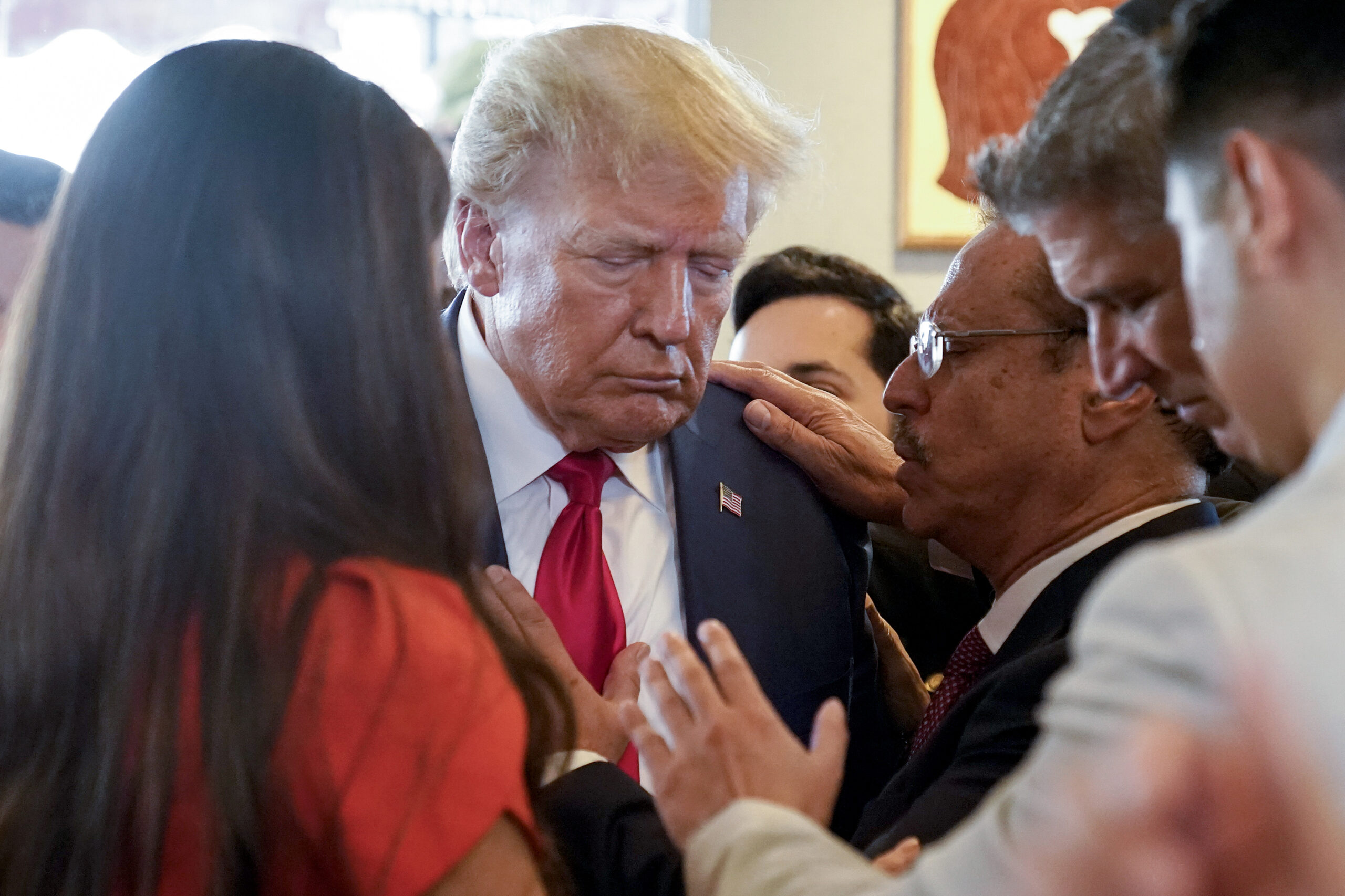 Former President Donald Trump prays with pastor Mario Bramnick, third from right, and others at Versailles restaurant on Tuesday, June 13, 2023, in Miami. Trump appeared in federal court Tuesday on dozens of felony charges accusing him of illegally hoarding classified documents and thwarting the Justice Department's efforts to get the records back. 