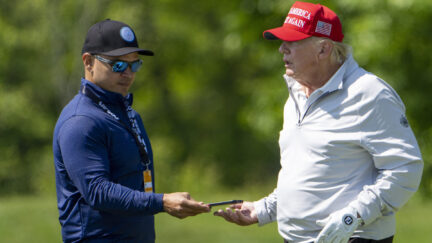 FILE - Walt Nauta, left, takes a phone from Former President Donald Trump during the LIV Golf Pro-Am at Trump National Golf Club, May 25, 2023, in Sterling, Va. Nauta is set to be arraigned on charges that he helped the former president hide classified documents that the Justice Department wanted back. Nauta was charged earlier this month alongside Trump in a 38-count indictment filed by Justice Department special counsel Jack Smith.