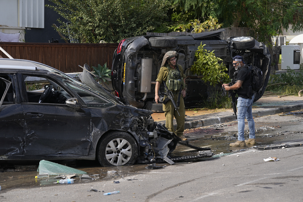 Israeli policeman and a soldier talk near the police station that was overrun by Hamas militants on Saturday, in Sderot, Israel, Sunday, Oct.8, 2023. Hamas militants stormed over the border fence Saturday, killing hundreds of Israelis in surrounding communities.