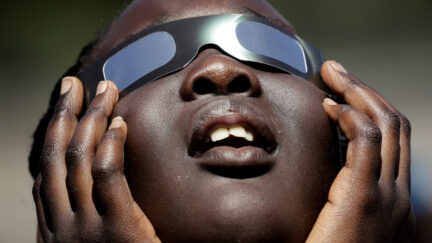 A child uses eclipse glasses in anticipation of 2017's solar eclipse.
