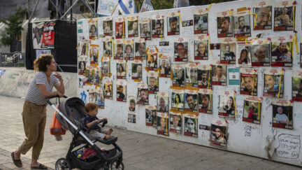 Passersby observe the photos of hostages held in the Gaza Strip that are plastered to the walls of a plaza known as Hostages Square in Tel Aviv, Israel, Friday, May 17, 2024. The Israeli military said Friday its forces rescued from Gaza the remains of three Israeli hostages taken by militants during the Oct. 7 attack, including 22-year-old German-Israeli Shani Louk, 28-year-old Amit Buskila, and 56-year-old Itzhak Gelerenter.