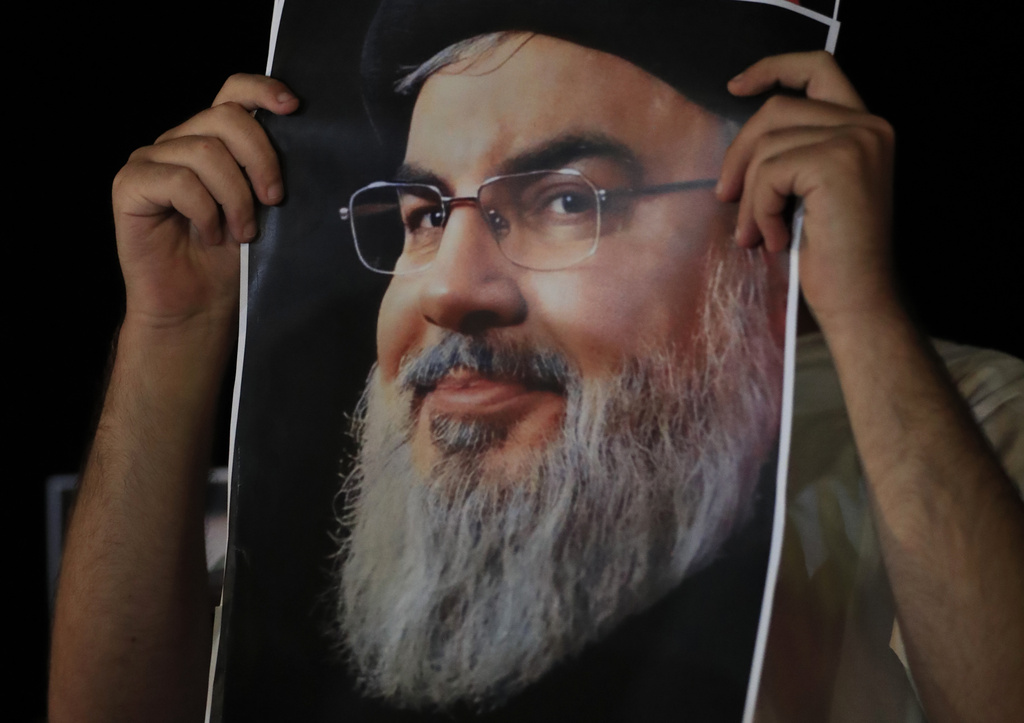A man covers his by a portrait of Hezbollah leader Sayyed Hassan Nasrallah during a protest in the southern port city of Sidon, Lebanon, Saturday, Sept. 28, 2024.
