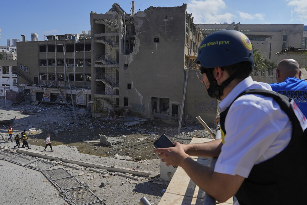 Israeli security forces and emergency teams work next to an unpopulated building after it was hit by a missile fired from Iran, in Haifa, Israel, Friday, June 20, 2025.