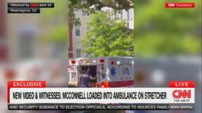 CNN image showing emergency personnel entering the back of an ambulance on a leafy street